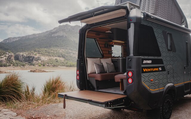 Utsikt fra baksiden av Venture S, med taket og Sunset Deck utfoldet, med fjell og vann i bakgrunnen.