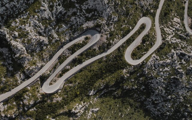 Aerial view of winding roads, surrounded by rocks and trees.