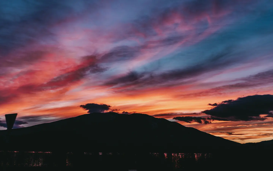 Blick auf einen wunderschönen Sonnenuntergang, im Hintergrund ist ein Berg zu sehen.
