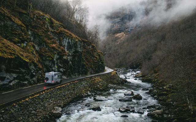 Blick auf einen Fluss in einer Schlucht, auf der linken Seite fährt ein HYMER ML-T CrossOver auf einer Sraße