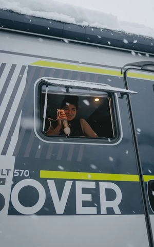 Blick von der Beifahrerseite außen in das Küchenfenster vom HYMER ML-T 570 CrossOver, Eine Frau ist im Fenster zu sehen