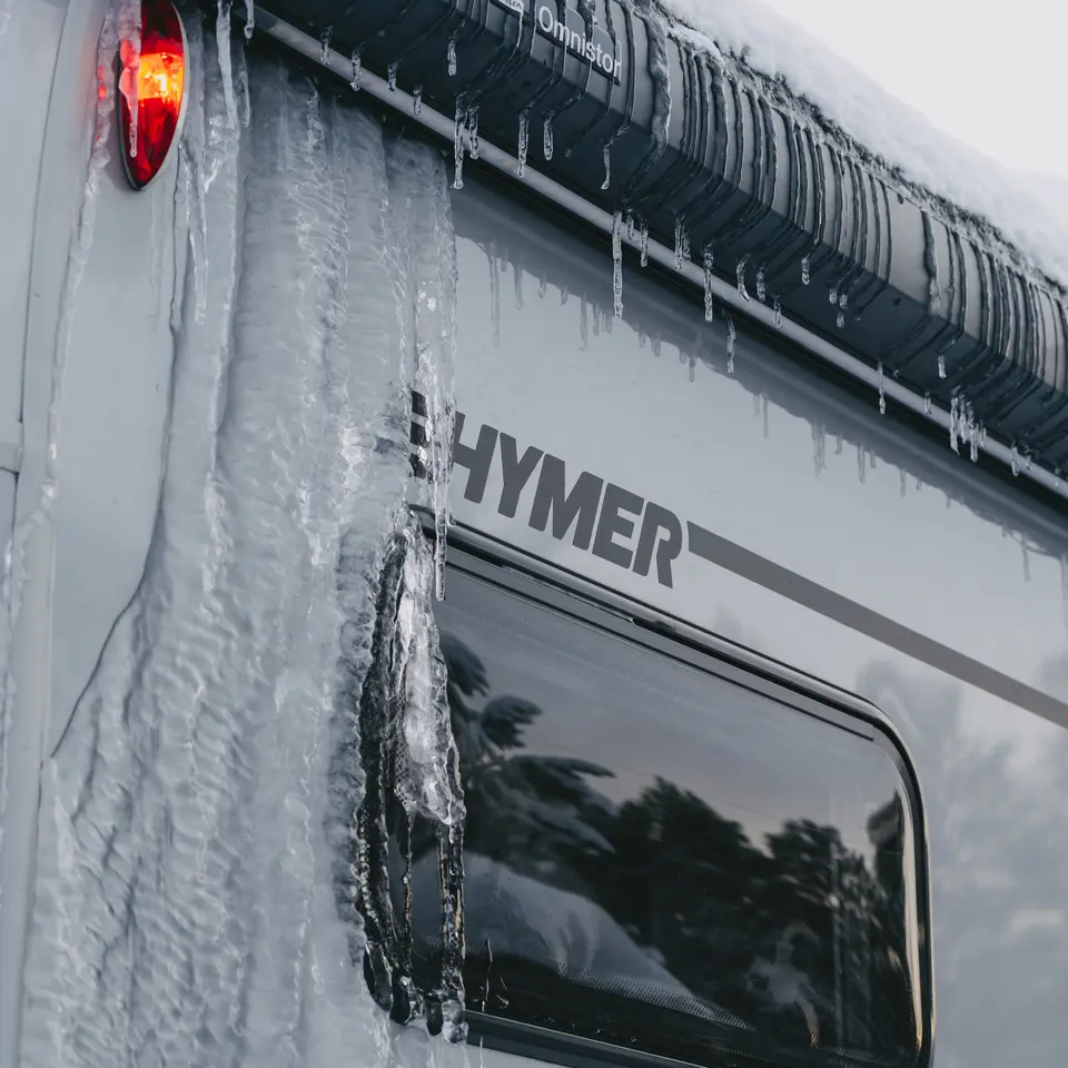 Blick von schräg rechts auf den HYMER B-MC T BlackLine, die Außenwand des Wohnmobils ist vereist.