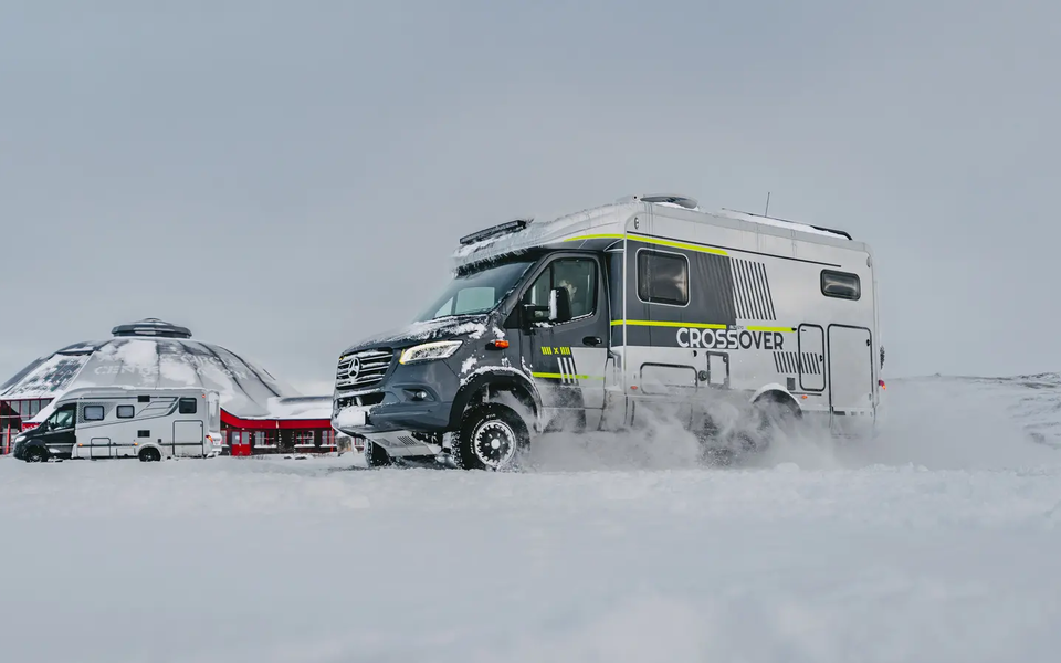Seitlicher Blick auf die Fahrerseite des HYMER ML-T CrossOver, das Fahrzeug parkt im Schnee, im Hintergrund ist der HYMER B-MC T BlackLine