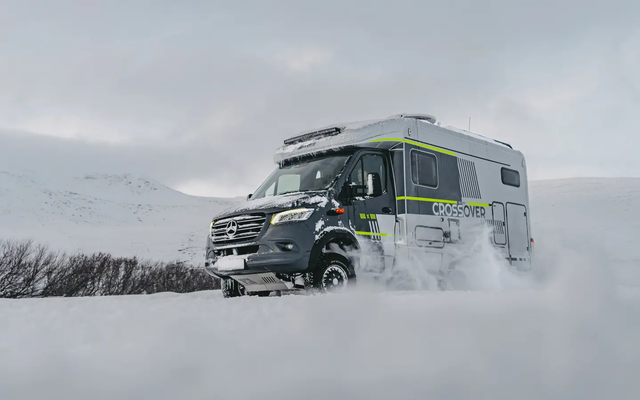 Schräger Blick von vorne rechts auf den HYMER ML-T 570 CrossOver, der durch eine winterliche, verschneite Landschaft fährt
