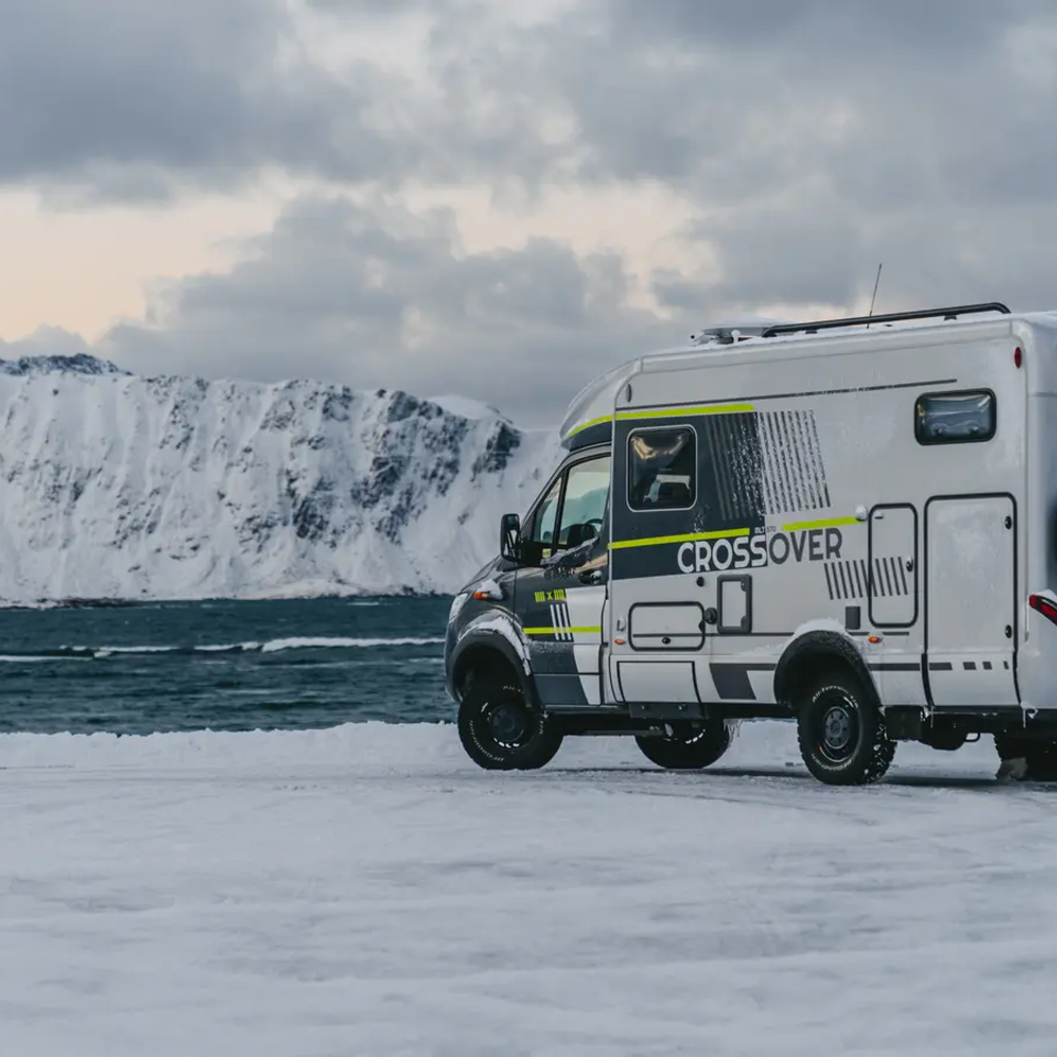 Seitlicher Blick auf den HYMER ML-T 570 CrossOver, im Hintergrund ist ein hoher Schneeberg und das Meer