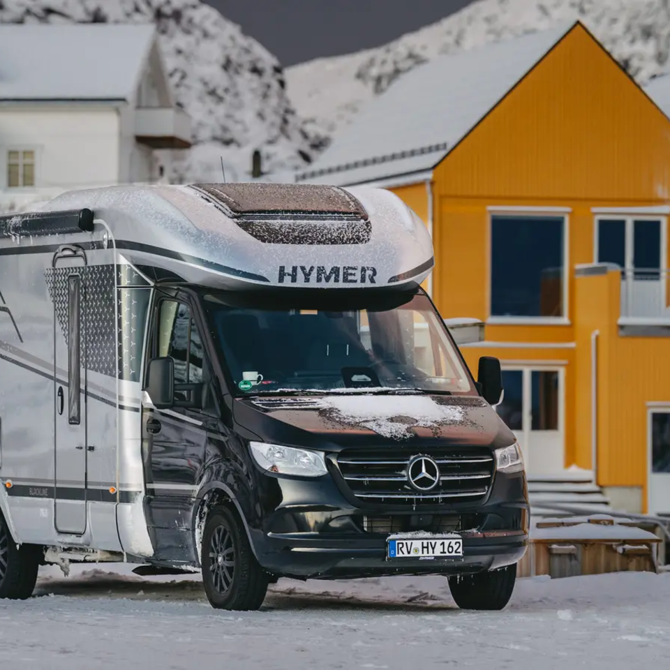 HYMER B-MC T BlackLine parkt auf einem verschneitem Weg, im Hintergrund sind gelbe Häuser