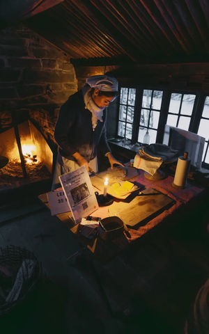 Frau in einer Hütte, im Hintergrund brennt Feuer im Kamin