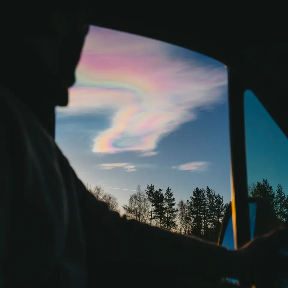 Blick aus einem Wohnmobilfenster auf irisierende Wolken