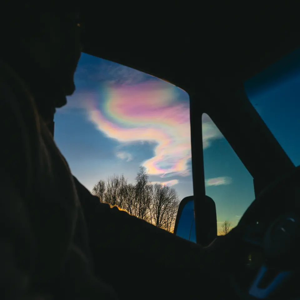 Blick aus einem Wohnmobilfenster auf irisierende Wolken