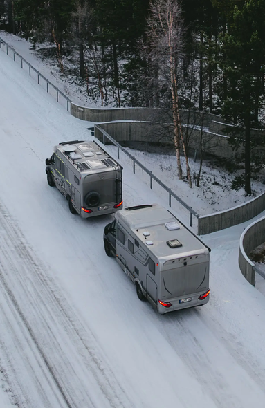 Luftblick auf HYMER B-MC T BlackLine und den HYMER ML-T 570 CrossOver, Sie parken auf einer verschneiten Straße