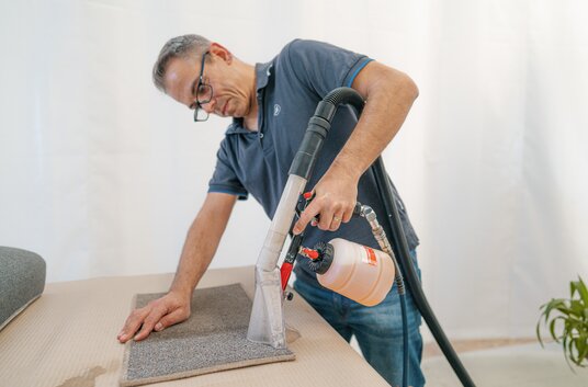 Manuel rengøring af gulvbelægningen i en HYMER autocamper med en vådstøvsuger
