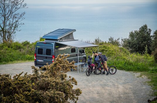 Campingsituation mit ausgefahrener Markise und Bikern vor dem Camper Van HYMER Yosemite auf Fiat Chassis 